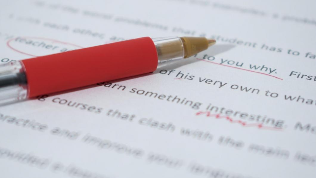 Een rode pen, liggend op een met deze pen gecorrigeerd document.